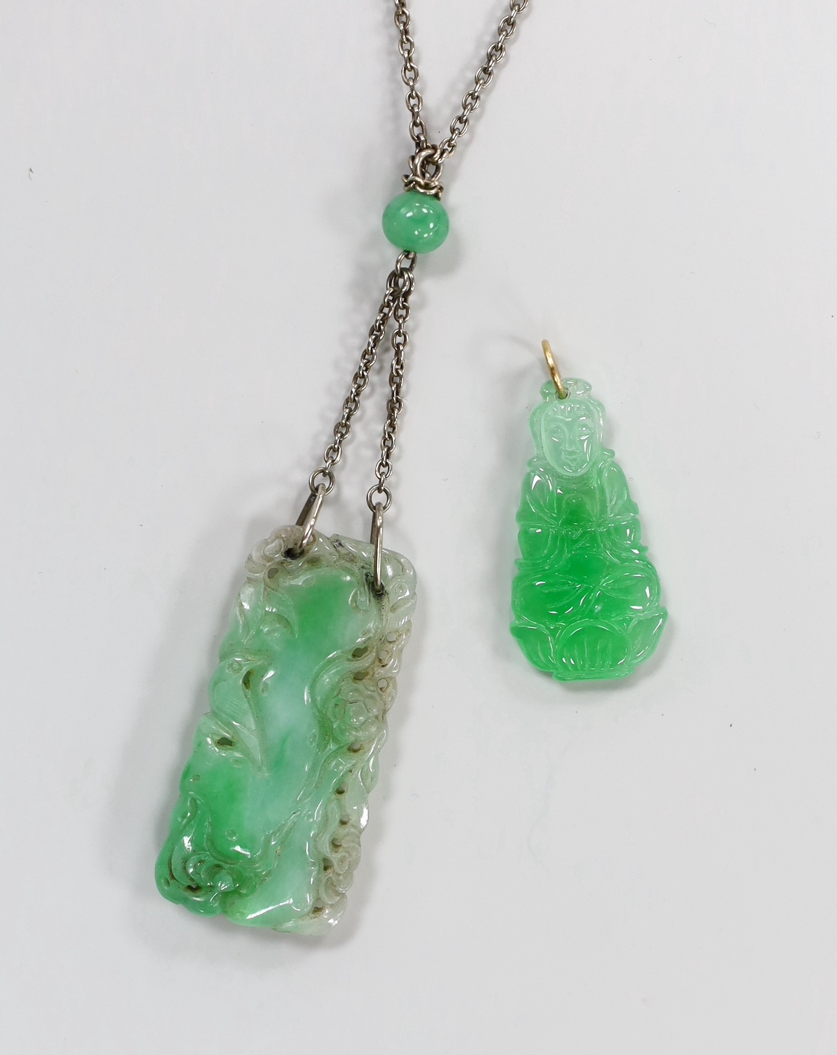 Two carved jade pendants, largest 47mm on a white metal chain.